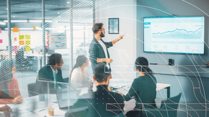 Man presenting a chart on a large screen to colleagues.