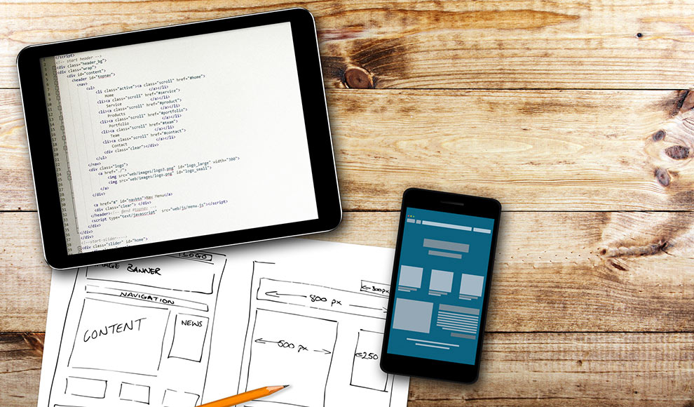 Tablet and phone displaying code and a website sketch.