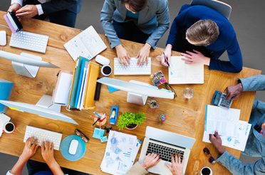 Group of people working at desks in an office environment.