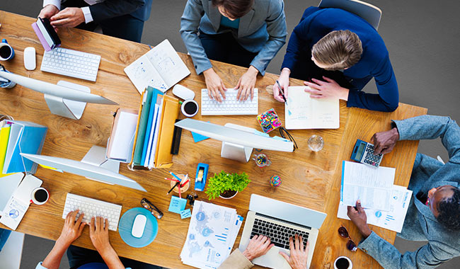 Group of people working at desks in an office environment.
