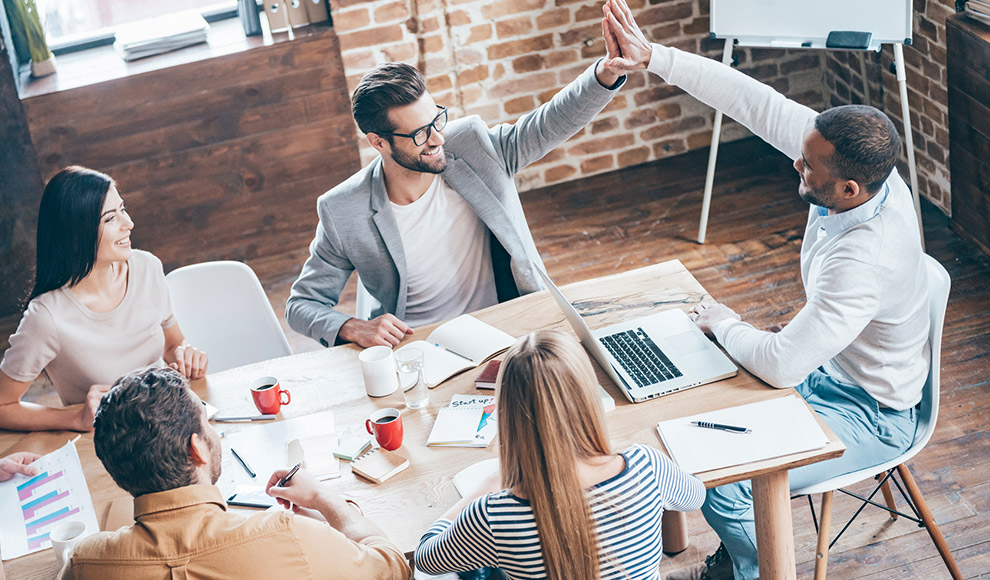 Team of people in an office giving high-fives.