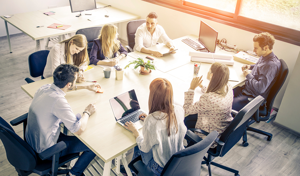 Team of people working together at a large table in an office.