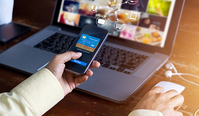 Person making an online payment with a credit card via phone and laptop.