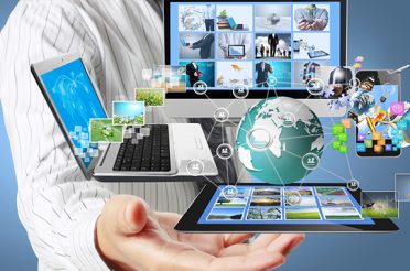 Person holding a computer, laptop, tablet, and phone in their hands.