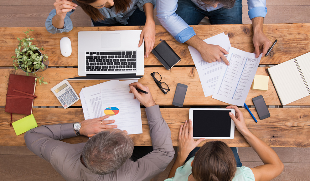 Team of people working together around a wooden table.