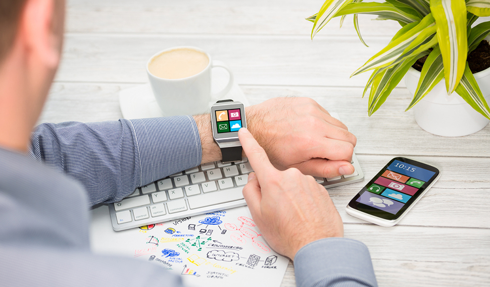 Man using a smartwatch while working at a desk.