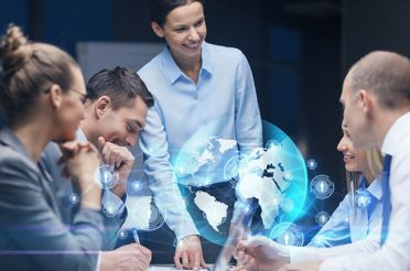 Group of businessmen discussing a global project with a holographic world projection in front of them.