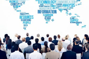 People at a business conference looking at a world map made of words.