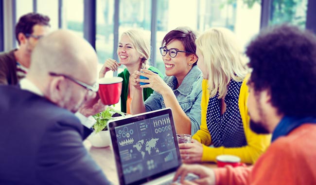 Group of people discussing data on a laptop while drinking coffee.