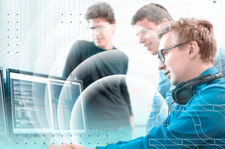 Three programmers discussing code on a monitor.