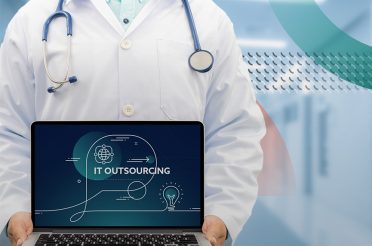 Doctor holding a laptop displaying the text 'IT Outsourcing'
