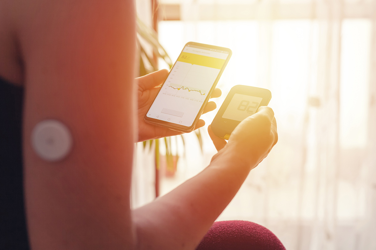 Person checking blood sugar levels with a glucometer and phone.