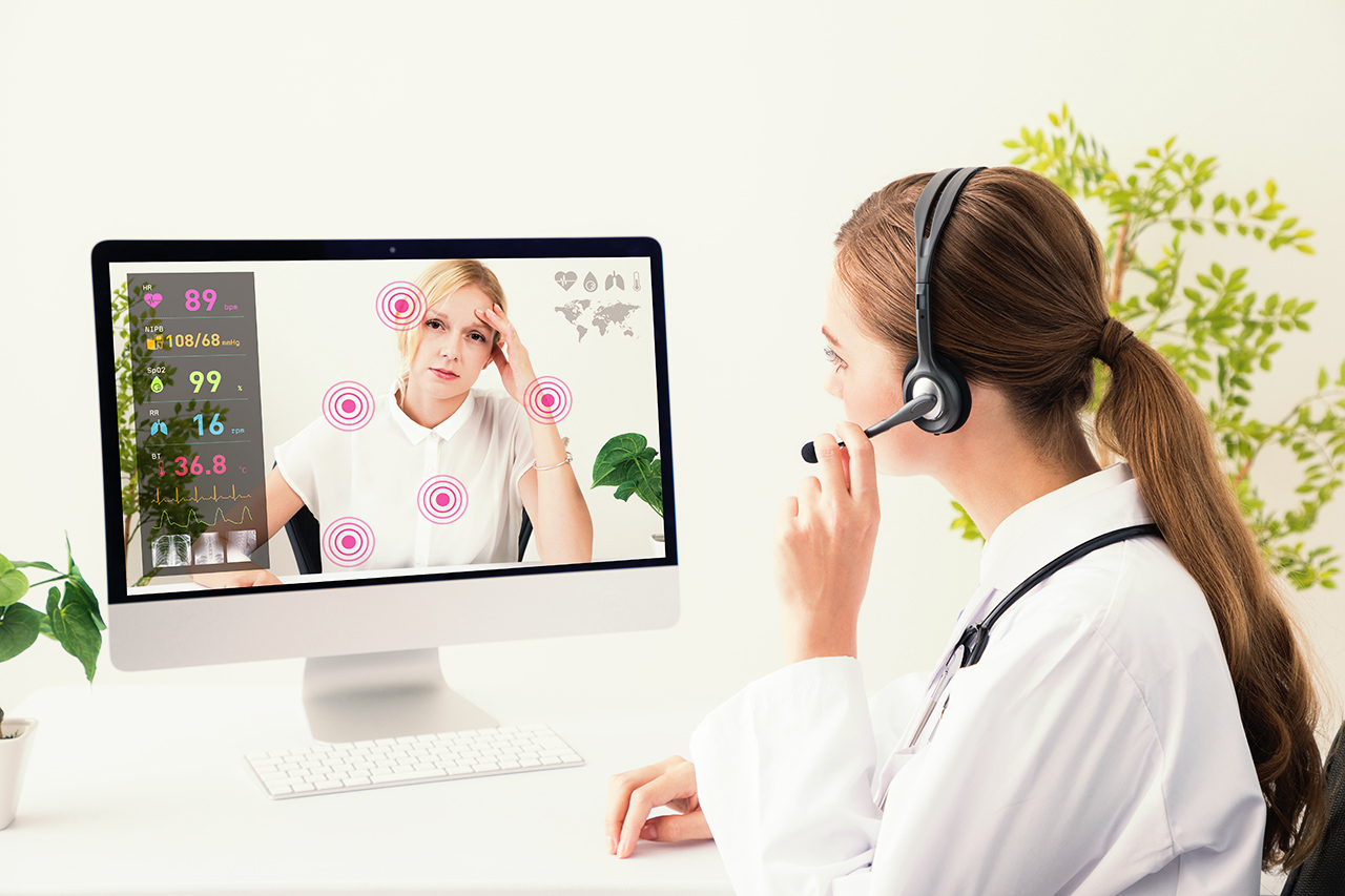 Female doctor with a headset conducting telemedicine while monitoring data.
