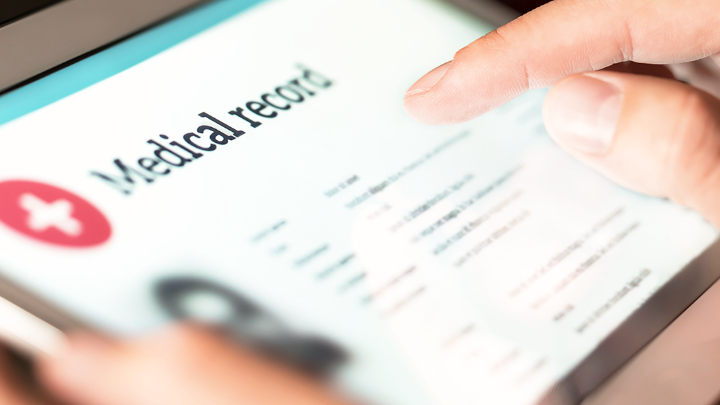 Finger touching a tablet screen with an electronic medical record.