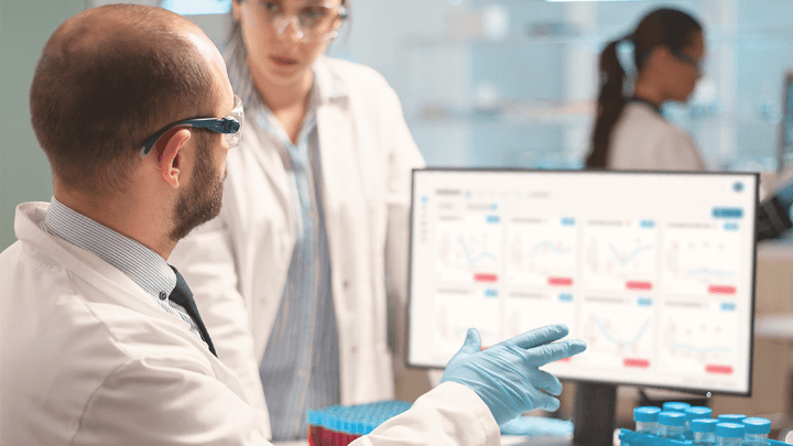 Scientists in a laboratory reviewing medical data on a computer.