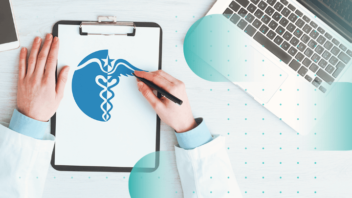 Doctor writing on a sheet with a medical symbol next to a laptop.