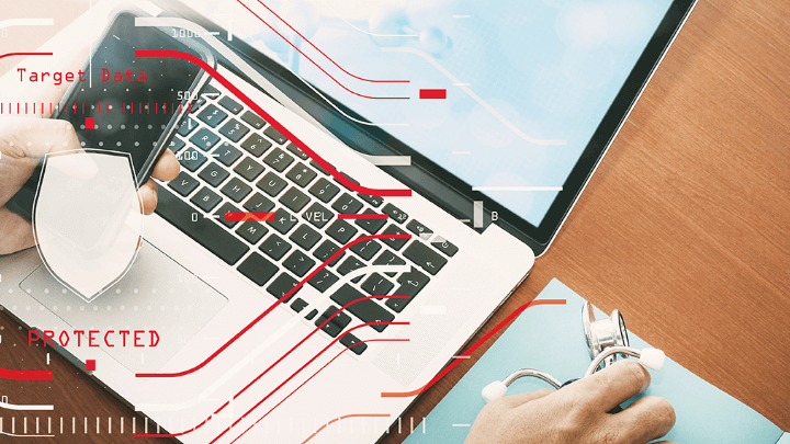 Doctor working on a laptop with holographic security elements.