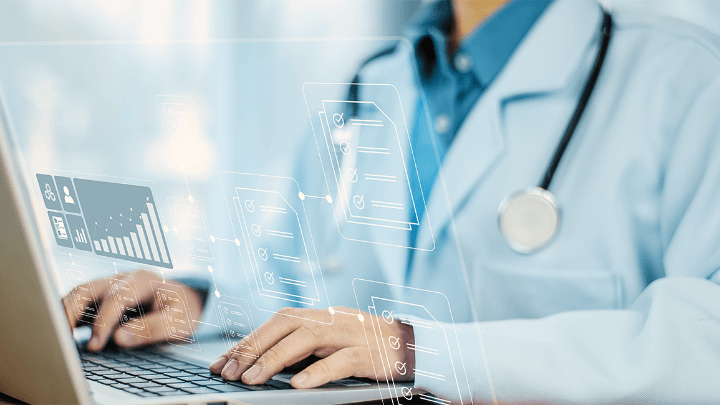 Doctor working on a laptop with holographic icons.