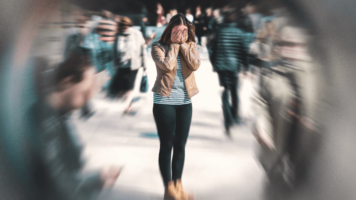 Woman holding her hands to her face in a crowd.