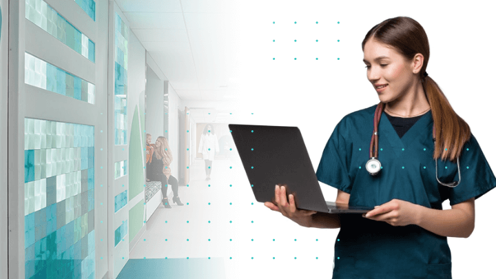 Doctor in a hospital corridor holding a laptop.