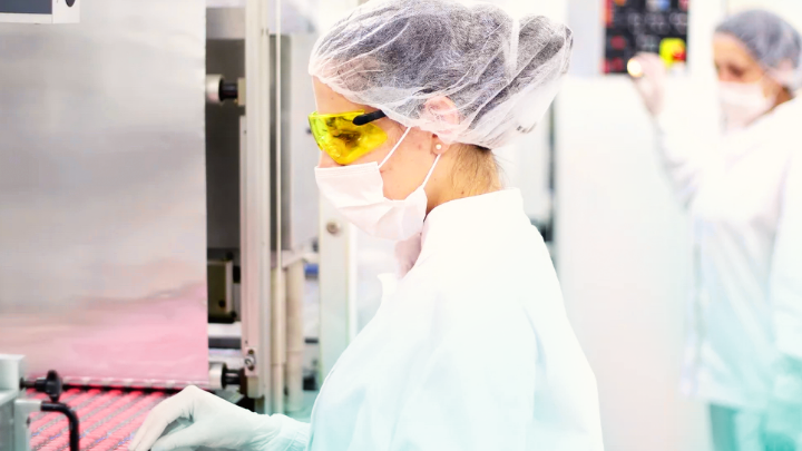 Medical professional in protective gear operating a machine.