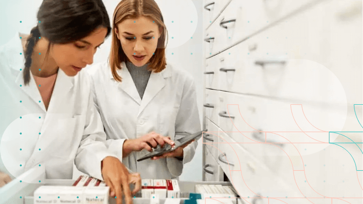 Two pharmacists examining medications in a drawer at a pharmacy.