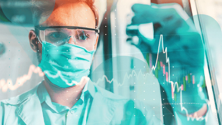 Scientist wearing a mask and safety goggles reviewing data.