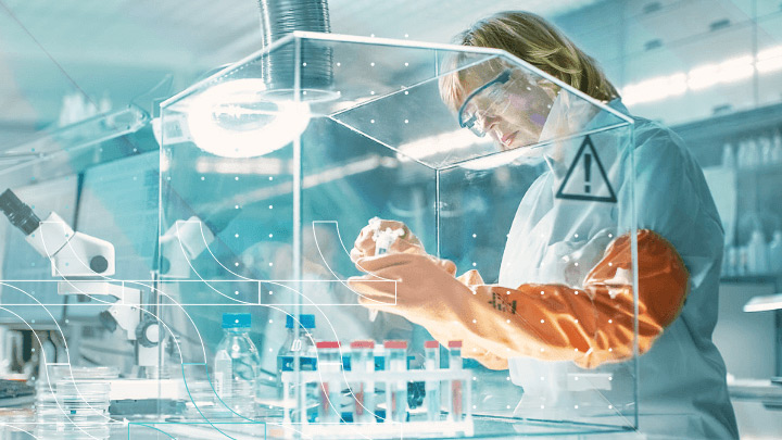 Scientist in a laboratory working with equipment under a protective screen.