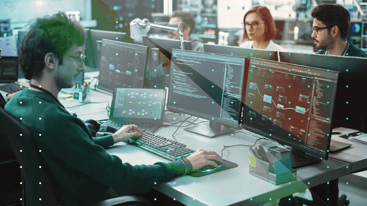Group of four people working on computers in an office.