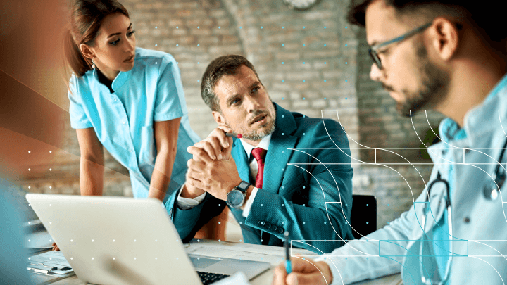Doctors and businesspeople discussing a project on a laptop.