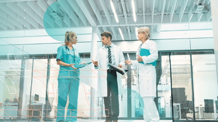 Three doctors discussing medical documents in a hospital corridor.