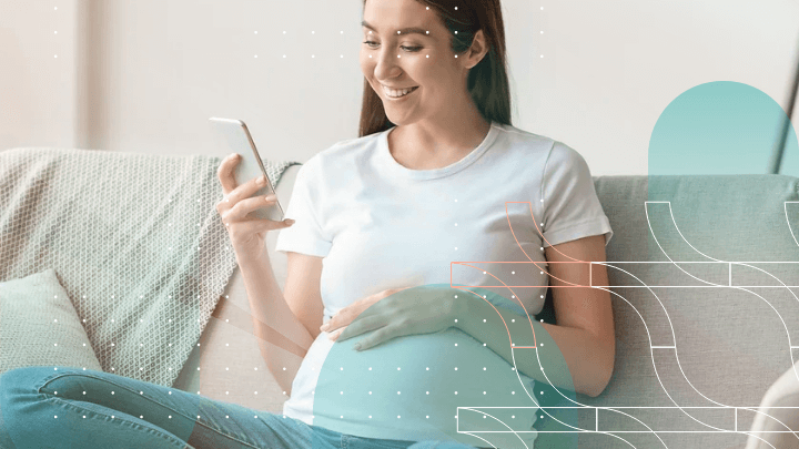 Pregnant woman sitting on a sofa using a smartphone.