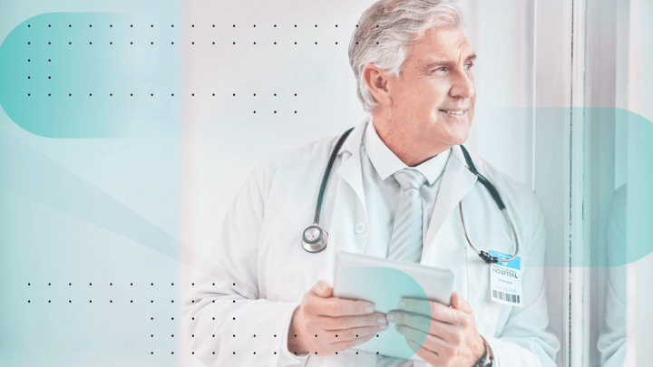 Smiling senior doctor in a white coat holding a tablet.