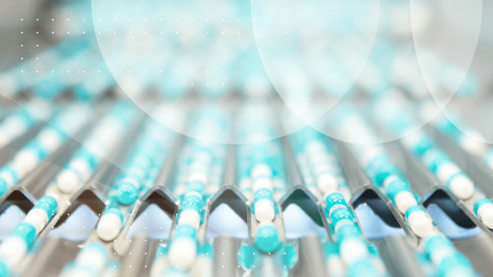Pharmaceutical capsules moving along a conveyor belt, symbolizing production.