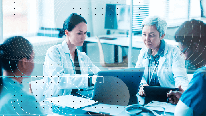Team of medical professionals holding a meeting while looking at a laptop.