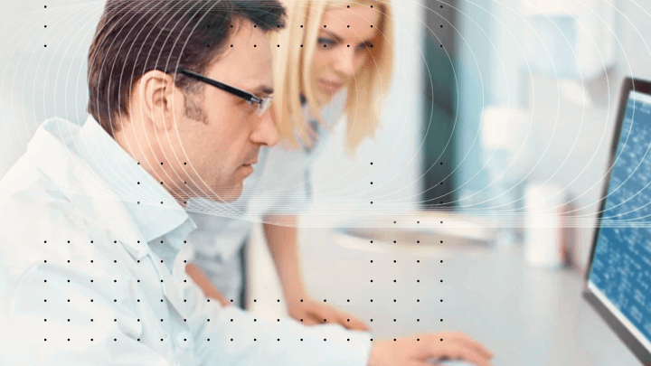 Two colleagues analyzing data while looking at a monitor.