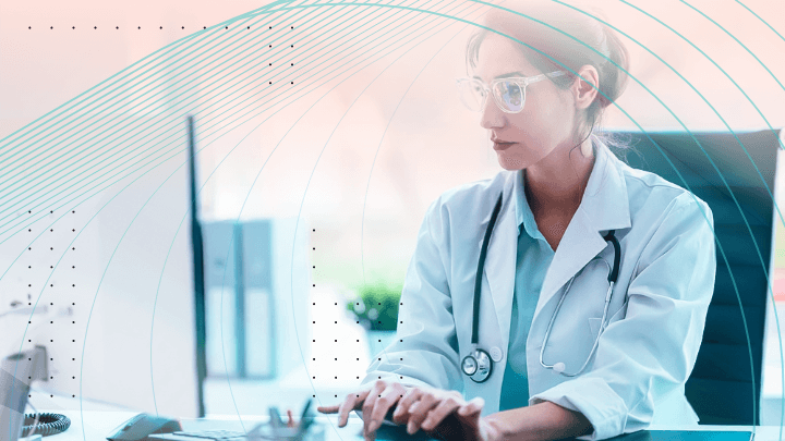 Female doctor in a white coat with a stethoscope working on a computer.
