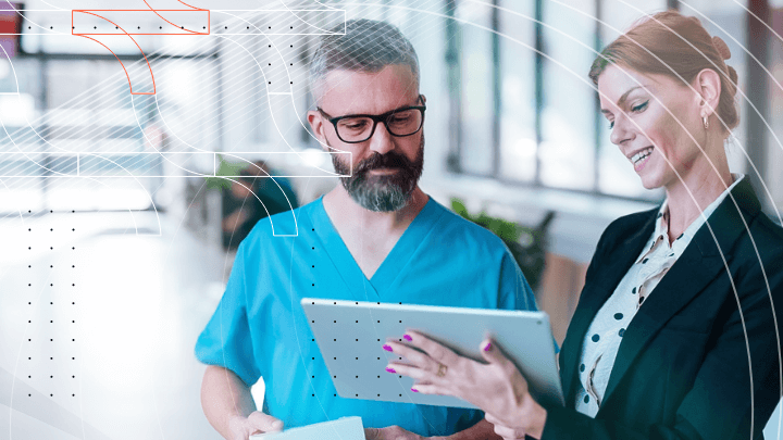 A man and a woman in medical attire looking at a tablet.