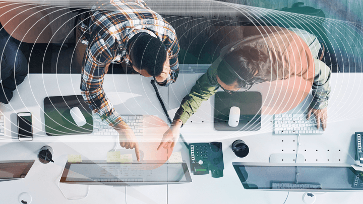 Two colleagues working on computers, viewed from a bird’s-eye perspective.