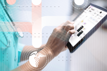 A doctor’s hand holds a tablet while the other hand touches the screen to enter medical data or work with patient information.