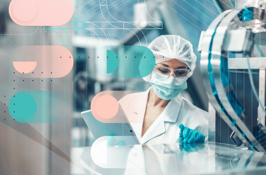 A woman in laboratory clothing and a mask working with a tablet next to a machine.